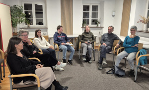 eine Gruppe von Menschen sitzen im Halbkreis auf Stuehlen