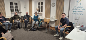 Mann steht im Raum uns spricht über ein projiziertes Bild an der Wand